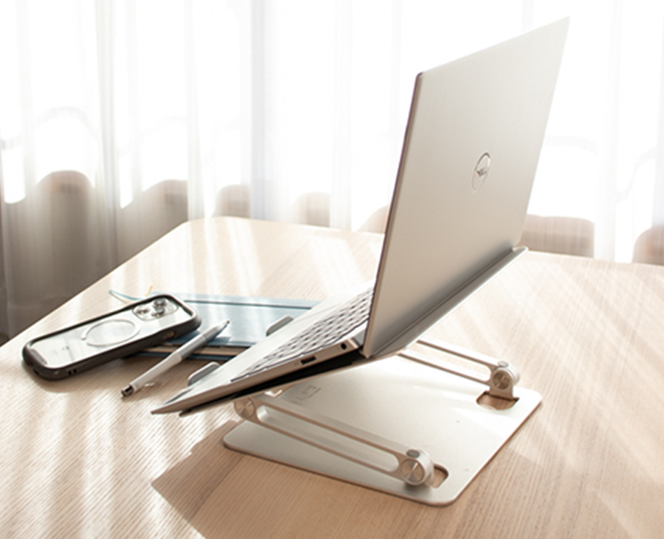 陽の光がさす机の上にあるPCと筆記用具
